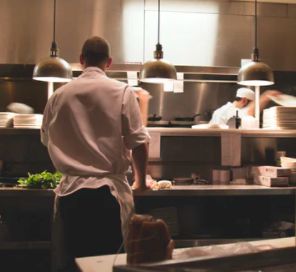 chef, kitchen and waitstaff work in a busy kitchen